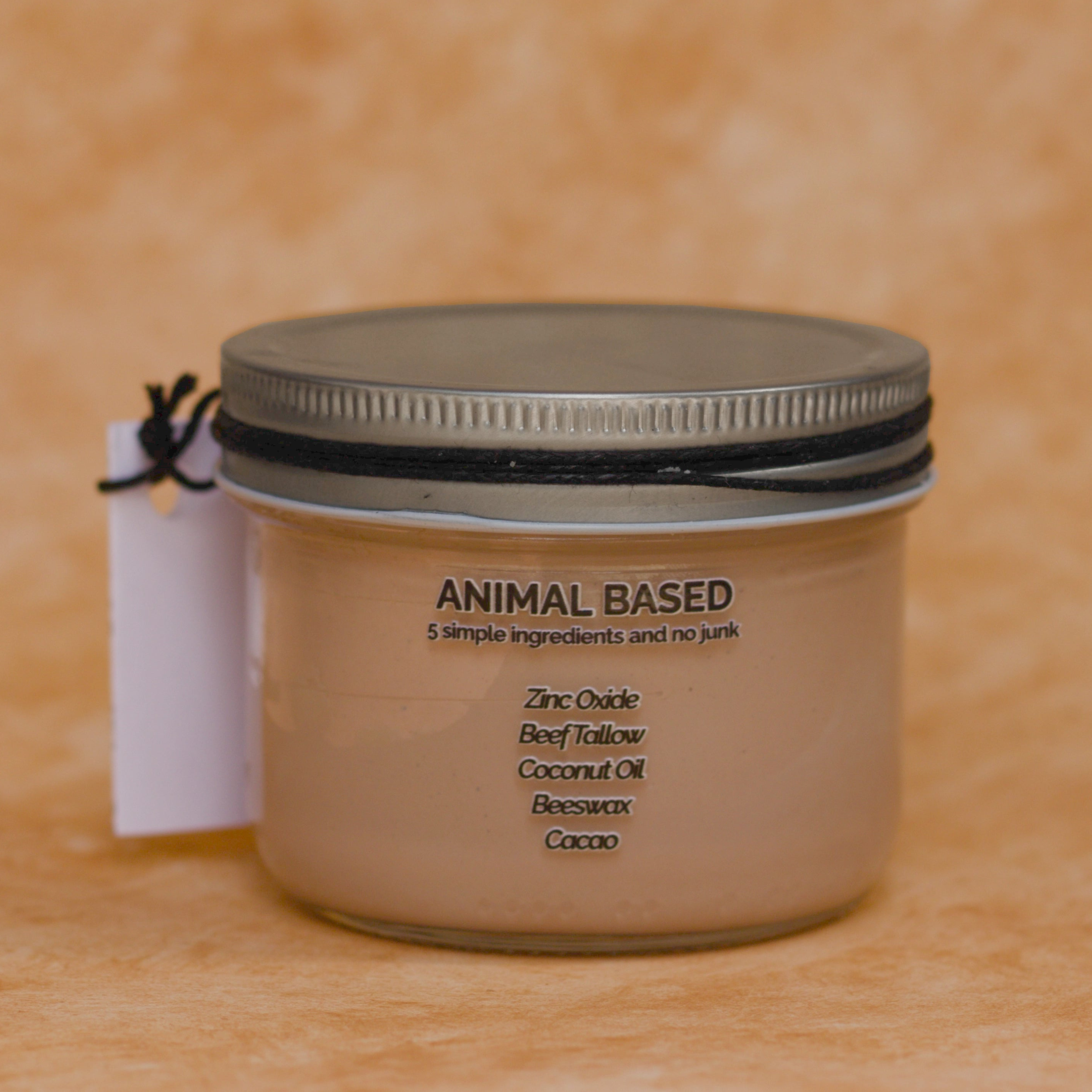 Back of 8 oz jar with a metal lid on a beige background.