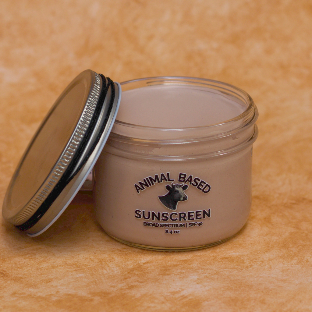 Jar of animal-based sunscreen with a metal lid on an a beige background