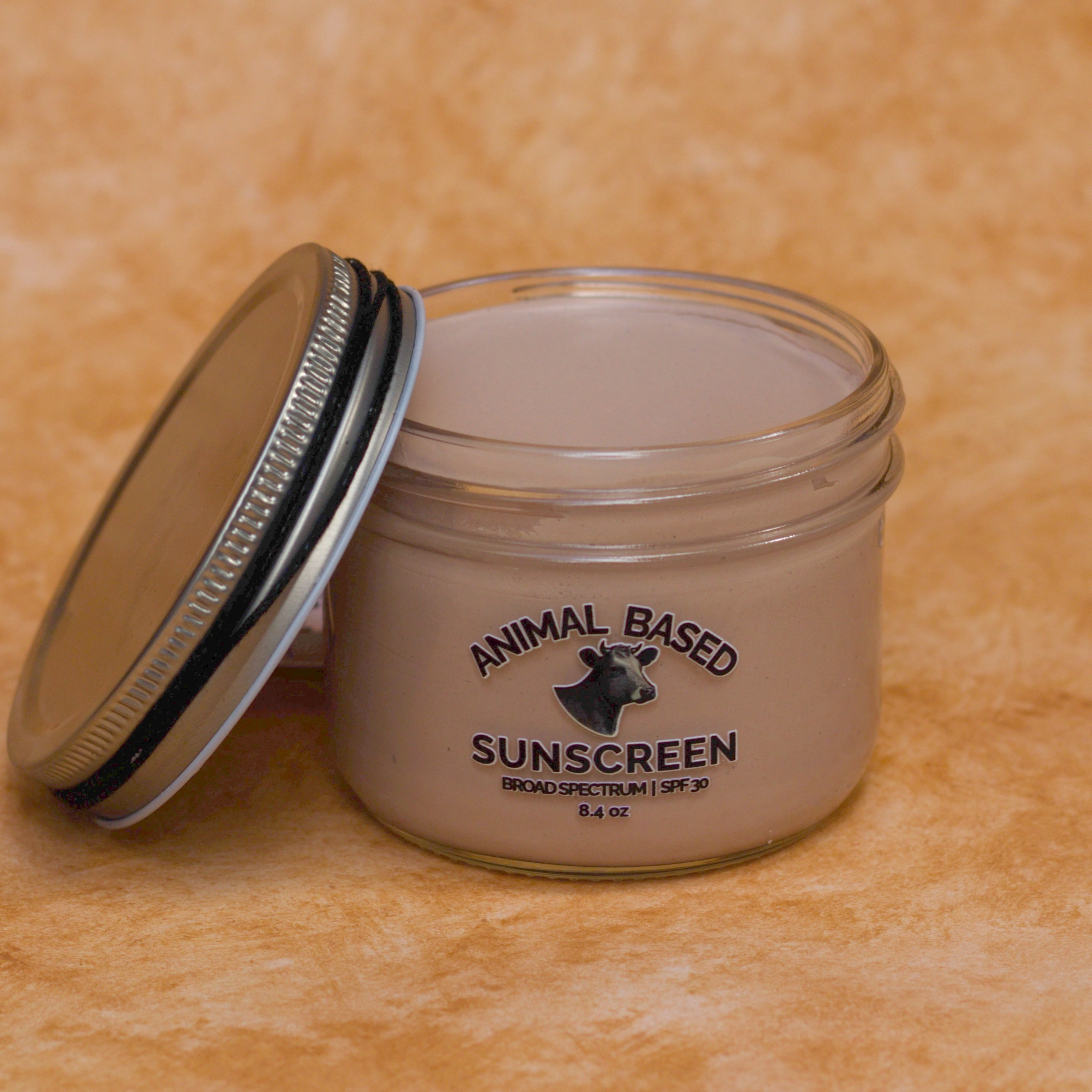Jar of animal-based sunscreen with a metal lid on an a beige background